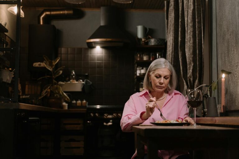 an elderly woman eating alone at home